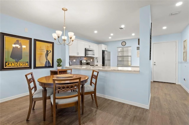 dining room featuring sink, light hardwood / wood-style flooring, and an inviting chandelier