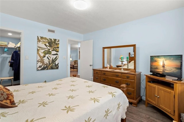 bedroom featuring dark hardwood / wood-style flooring, a walk in closet, and a closet