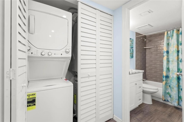 washroom with dark wood-type flooring and stacked washer and clothes dryer