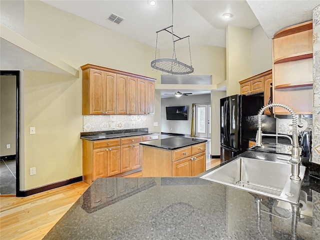 kitchen featuring light wood-type flooring, dark stone counters, ceiling fan, sink, and hanging light fixtures