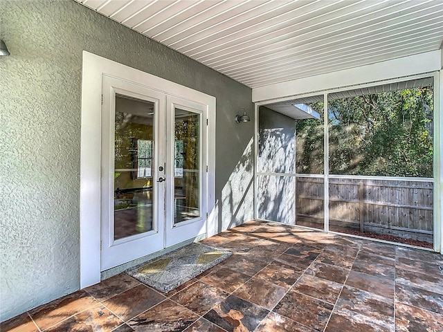 unfurnished sunroom with french doors, a healthy amount of sunlight, and wood ceiling