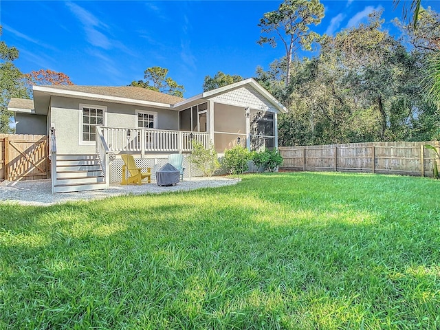 rear view of property featuring a deck, a lawn, and a sunroom