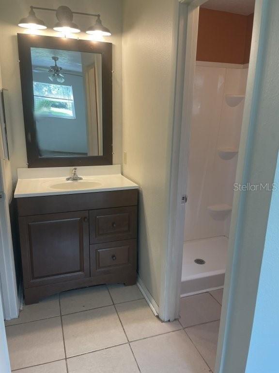 bathroom with a shower, vanity, tile patterned floors, and ceiling fan