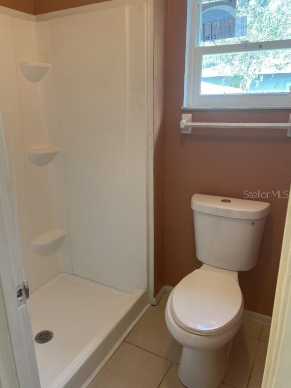 bathroom with tile patterned floors, toilet, and walk in shower