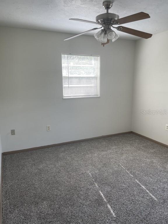 carpeted spare room with a textured ceiling and ceiling fan