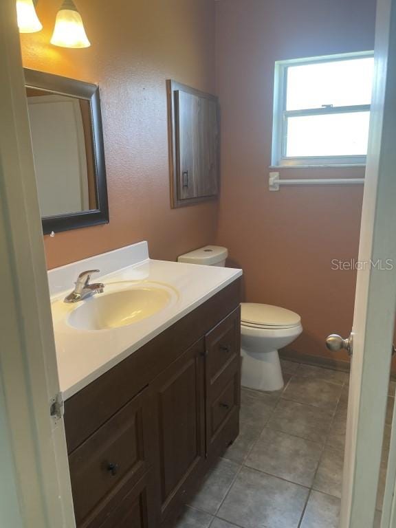 bathroom with tile patterned flooring, vanity, and toilet