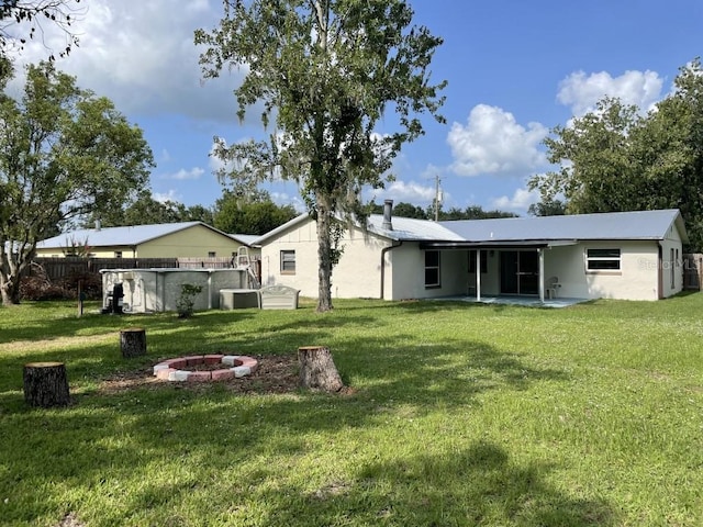 back of house featuring a yard, a fire pit, and a patio area