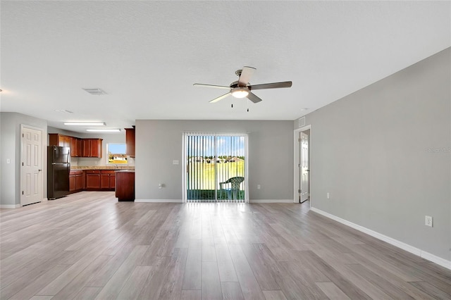 unfurnished living room with ceiling fan, a textured ceiling, and light wood-type flooring