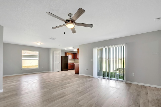 unfurnished living room featuring ceiling fan, light hardwood / wood-style floors, and a textured ceiling