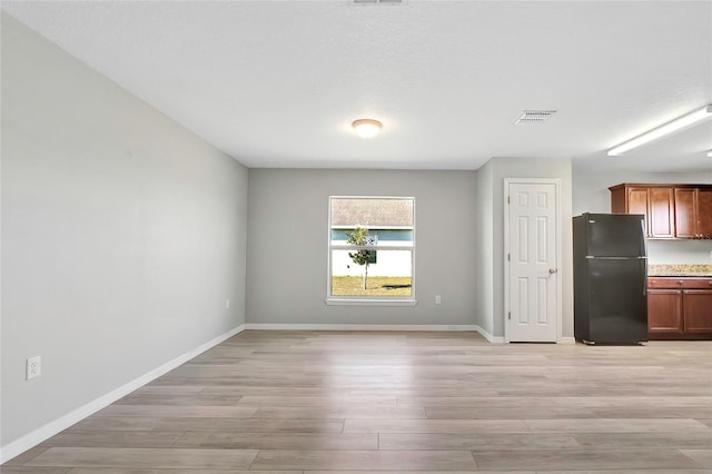 interior space featuring light wood-type flooring and a textured ceiling