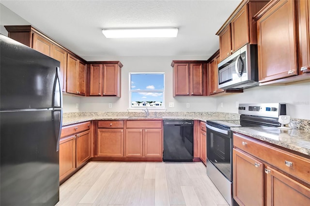 kitchen with black appliances, light wood-type flooring, sink, and a textured ceiling