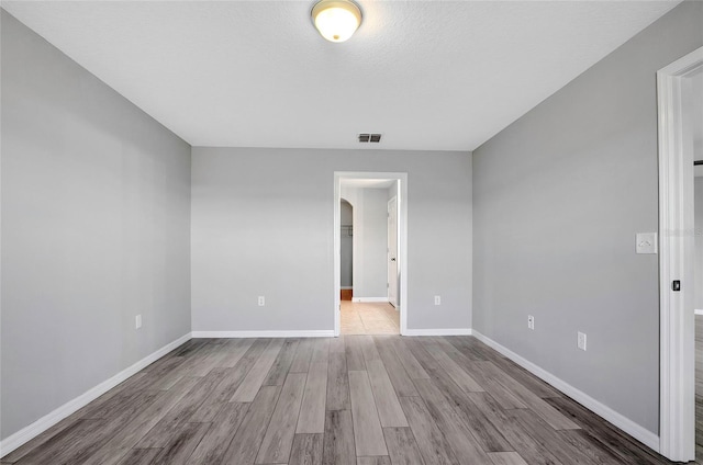 unfurnished room featuring a textured ceiling and light wood-type flooring