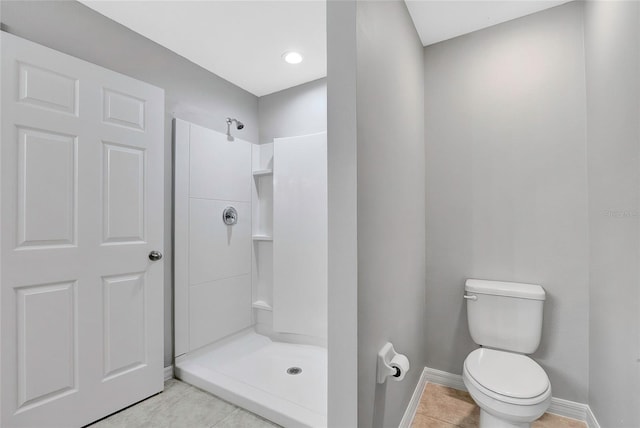 bathroom with toilet, a shower, and tile patterned floors