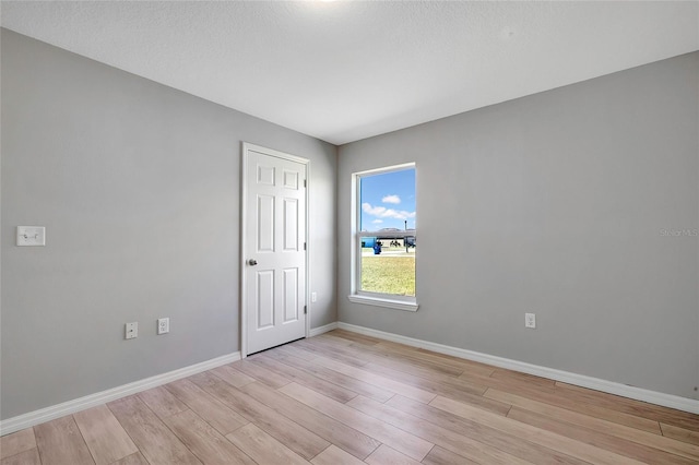 empty room featuring a textured ceiling and light hardwood / wood-style flooring