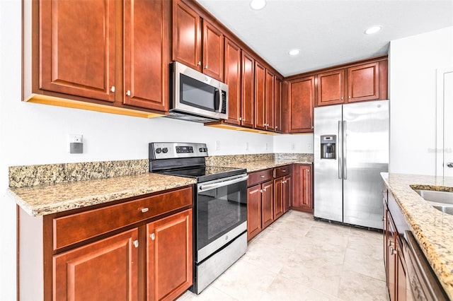 kitchen with light tile patterned floors, stainless steel appliances, a textured ceiling, and light stone countertops