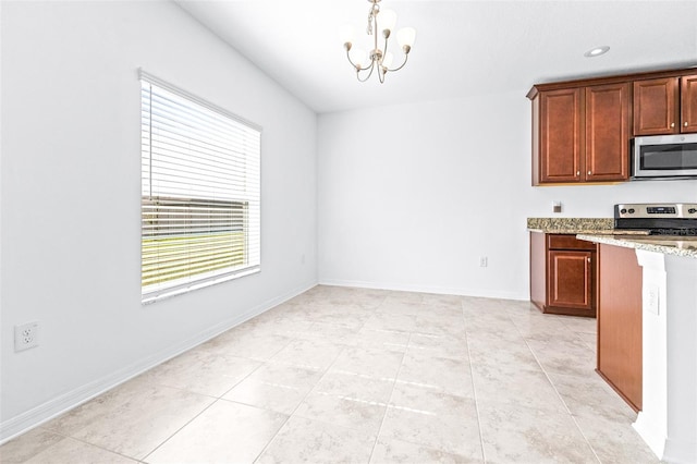 kitchen featuring stainless steel appliances, a chandelier, light stone counters, and light tile patterned floors