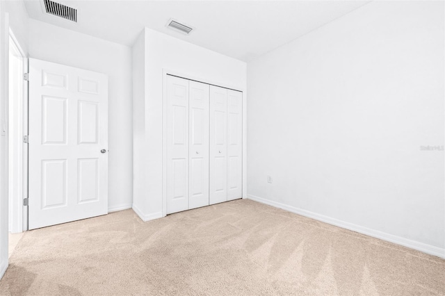 unfurnished bedroom with light colored carpet and a closet