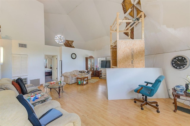 living room with hardwood / wood-style flooring, plenty of natural light, and high vaulted ceiling