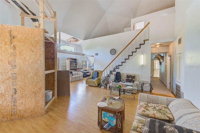 living room featuring high vaulted ceiling and light hardwood / wood-style floors