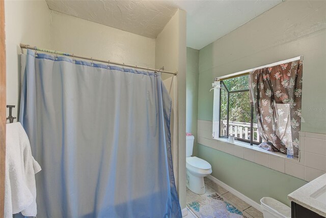 7923 18th Ave E, Palmetto, FL 34221 - bathroom featuring toilet, tile patterned floors, tile walls, vanity, and a wainscoted wall