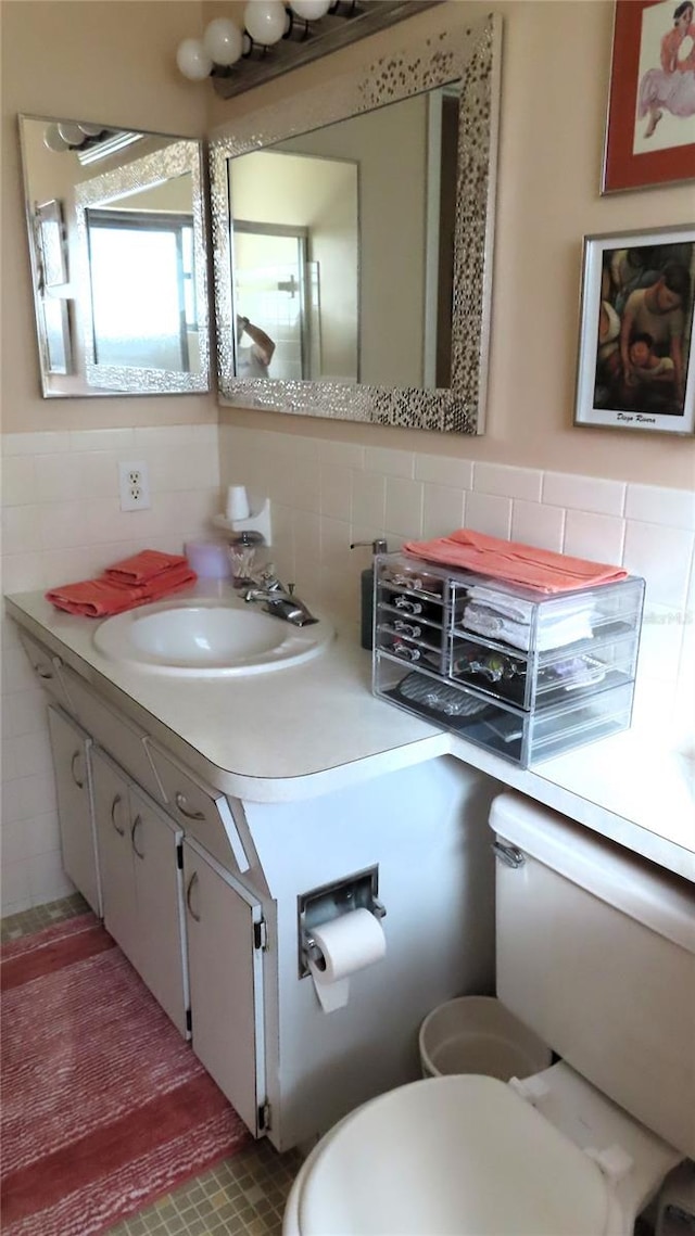 bathroom with vanity, decorative backsplash, toilet, and tile walls