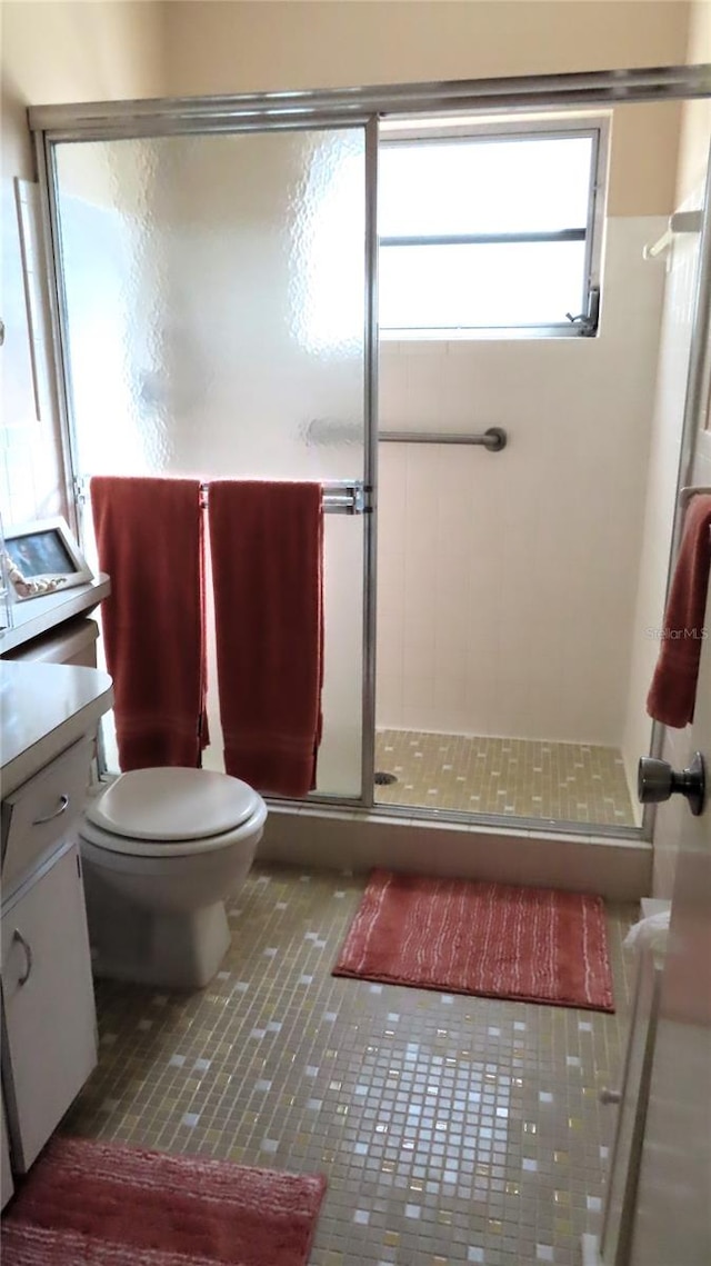 bathroom featuring tile patterned floors, vanity, a shower with shower door, and toilet