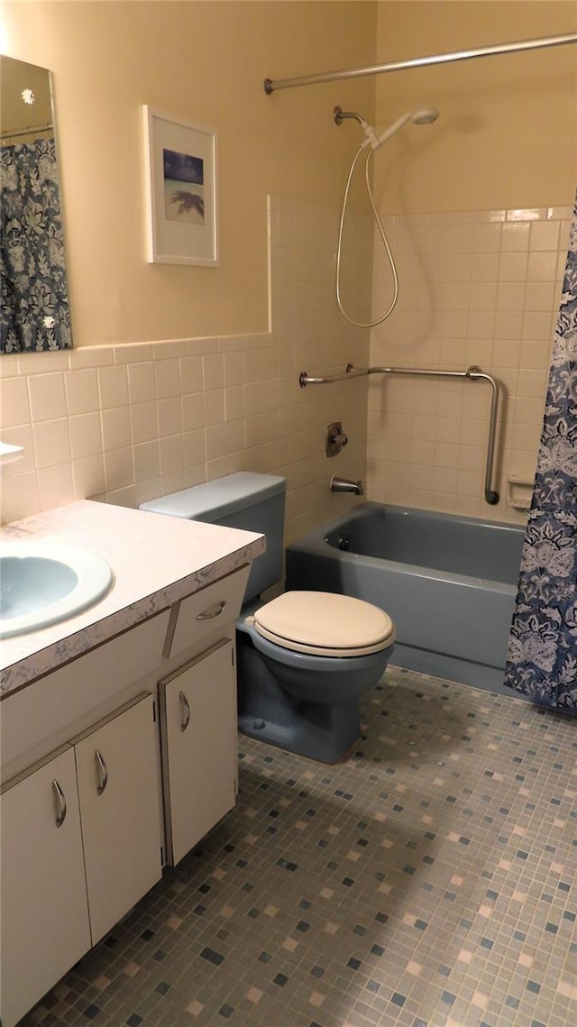 full bathroom with tile patterned floors, vanity, shower / bath combo with shower curtain, toilet, and tile walls