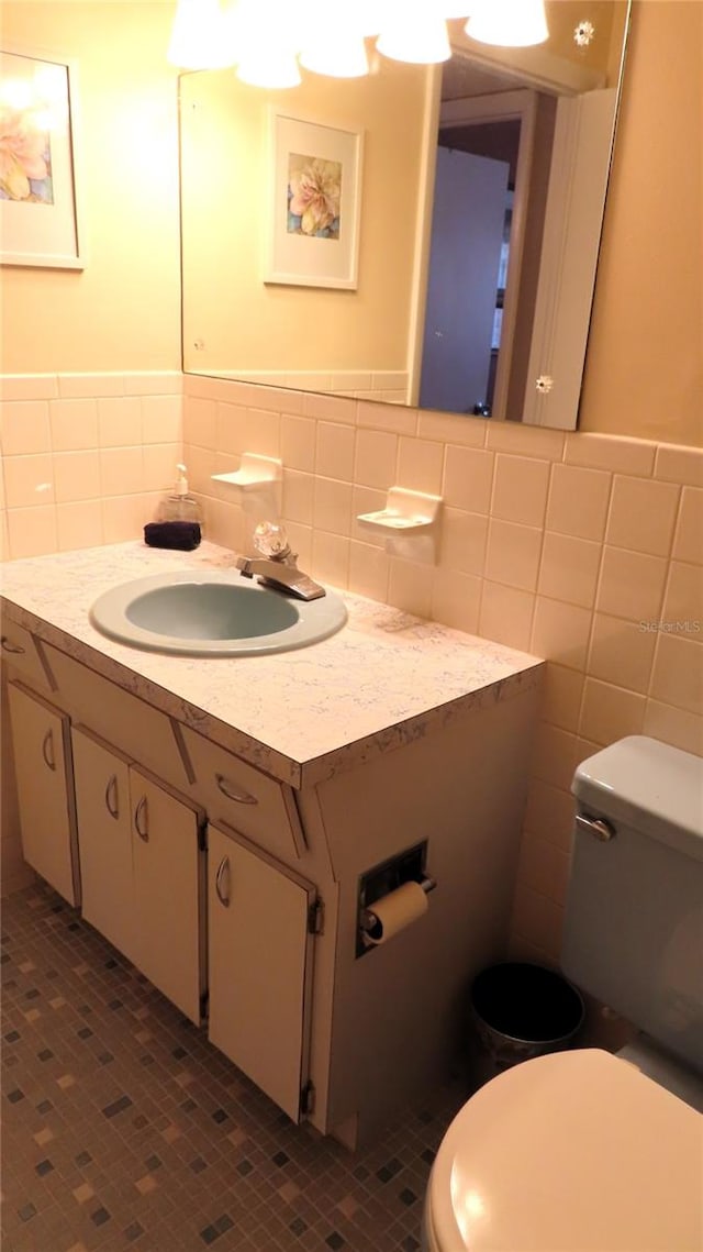 bathroom with tile patterned floors, vanity, tile walls, and toilet