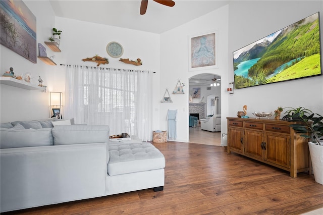 living room with dark wood-type flooring, ceiling fan, and a towering ceiling