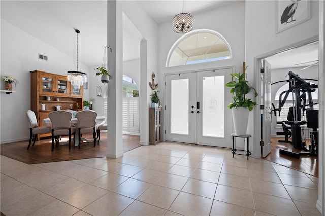 entrance foyer featuring a notable chandelier, high vaulted ceiling, french doors, and light tile patterned flooring