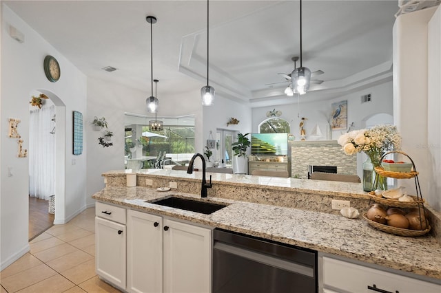 kitchen featuring sink, light stone counters, light tile patterned floors, a raised ceiling, and white cabinets