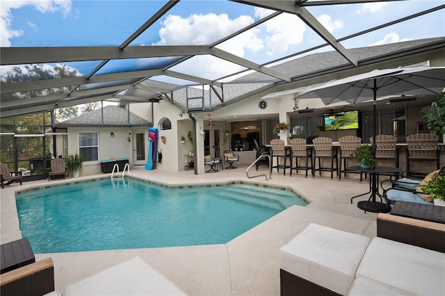 view of pool featuring a bar, glass enclosure, and a patio