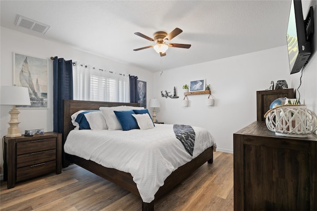 bedroom with hardwood / wood-style flooring, ceiling fan, and a textured ceiling