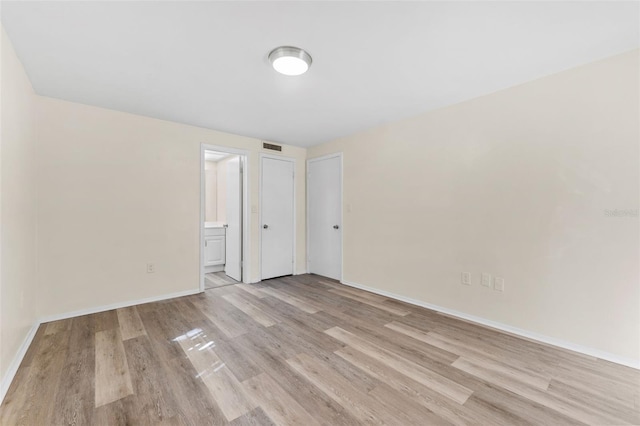 unfurnished bedroom with light hardwood / wood-style floors and ensuite bath