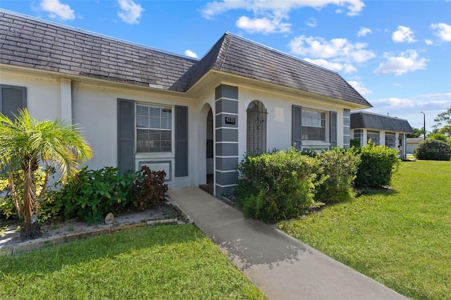 4220 Sheldon Pl Unit 4220, New Port Richey, FL 34652 - property entrance with stucco siding, a yard, mansard roof, and a shingled roof