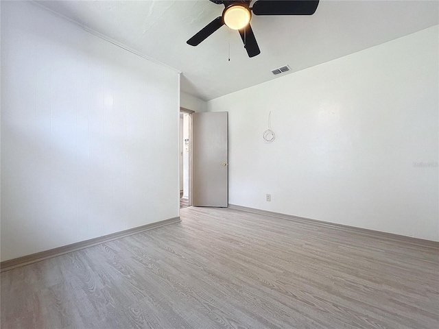 spare room with ceiling fan, vaulted ceiling, and light wood-type flooring