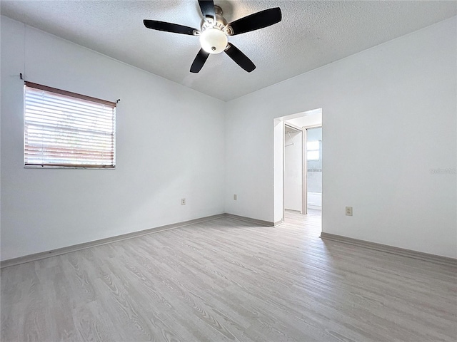 empty room featuring a textured ceiling, light wood-type flooring, and ceiling fan