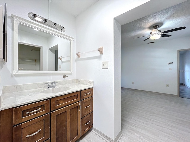 bathroom featuring vanity, wood-type flooring, a textured ceiling, and ceiling fan