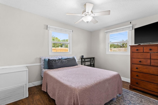 bedroom featuring multiple windows, ceiling fan, dark wood-type flooring, and a textured ceiling