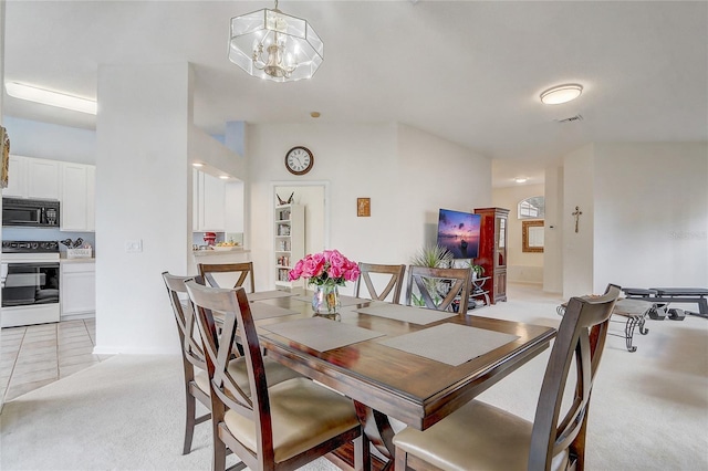 dining room featuring light carpet and a chandelier