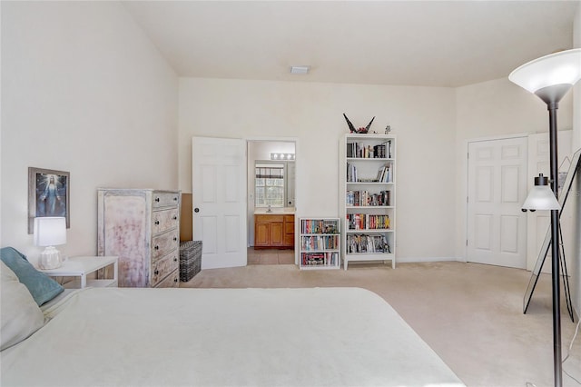 bedroom with light colored carpet and ensuite bathroom