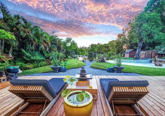 view of community featuring a deck with water view and a lawn