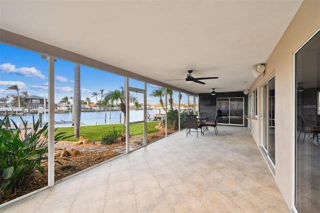 unfurnished sunroom featuring ceiling fan and a water view