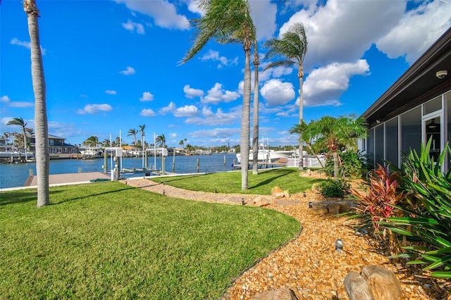 view of yard with a sunroom, a boat dock, and a water view