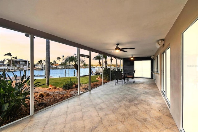 unfurnished sunroom with a water view and ceiling fan