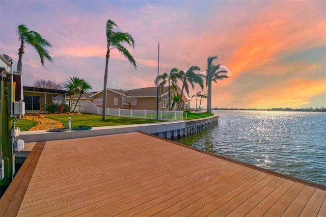 view of dock with a yard and a water view