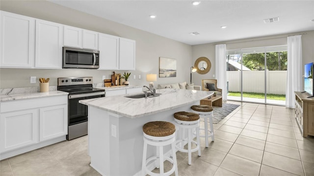 2472 Mellow Ln, Clearwater, FL 33765 - kitchen featuring appliances with stainless steel finishes, a sink, an island with sink, white cabinetry, and light stone countertops