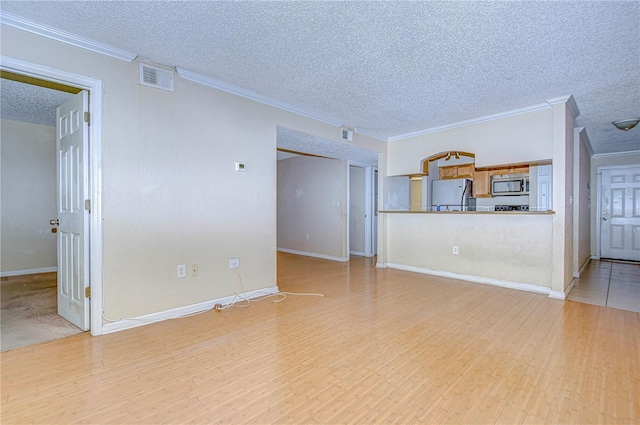 unfurnished living room with light wood-type flooring, a textured ceiling, and ornamental molding