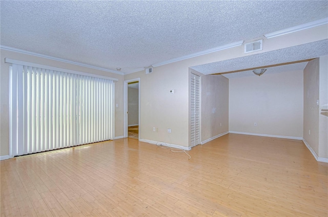 spare room with light hardwood / wood-style floors, ornamental molding, and a textured ceiling