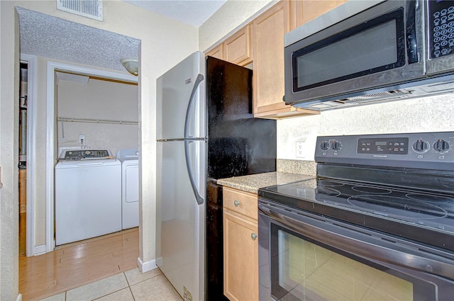 kitchen featuring electric range, light brown cabinets, light tile patterned floors, and washer and dryer